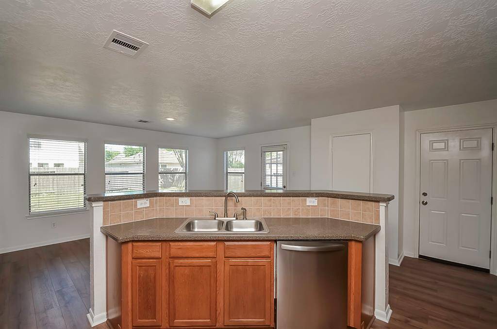 A welcoming breakfast bar provides ample seating in this home. With its oversized kitchen, brand-new appliances, and a pantry, there's so much to offer. The consistent flooring throughout adds to the cohesive design. To the right, a door leads to the garage, ensuring easy access.