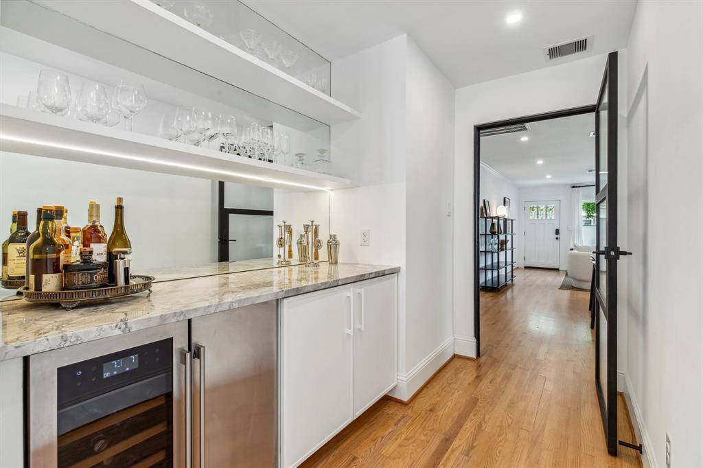 Entertain with ease thanks to the fantastic butler's pantry featuring white cabinetry and shelving, a Super White Calacatta Dolomite countertop, a beverage center and a wine refrigerator.
