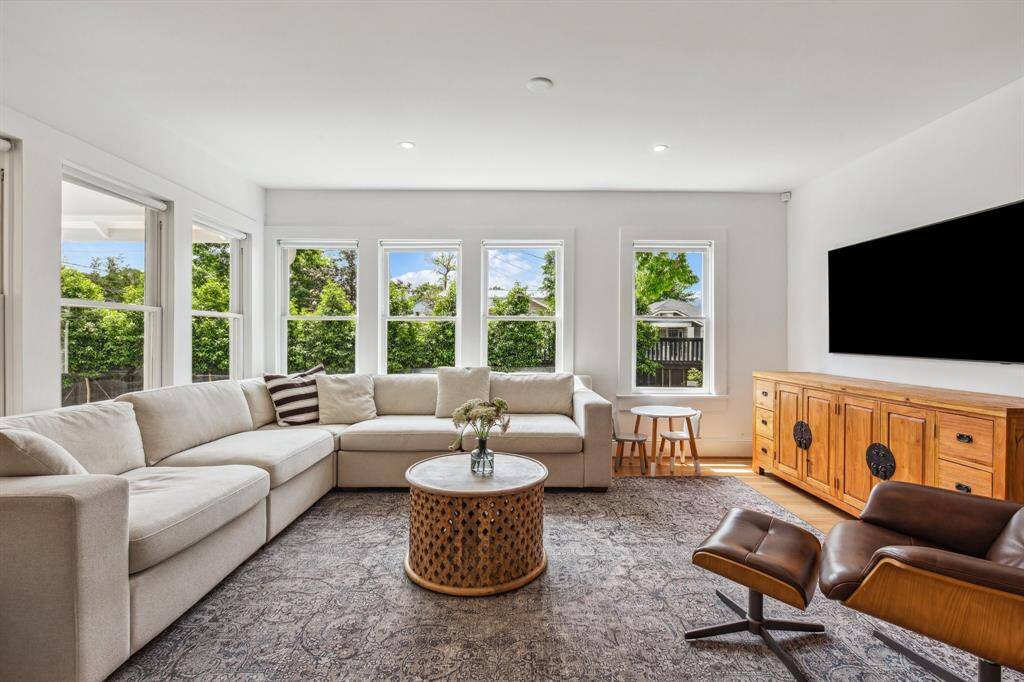 Seven original south- and east-facing windows with roller shades frame wonderful natural light and leafy views in the family room with 26 Holly trees in the backyard providing even more privacy.