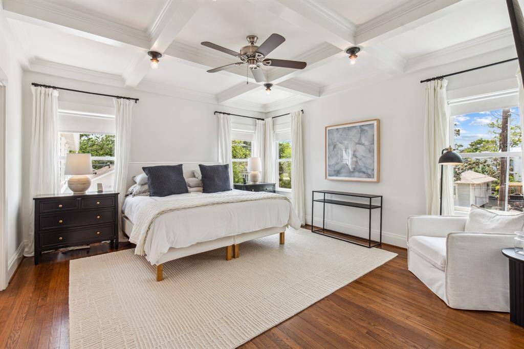 This upper-level secondary bedroom features a large closet, ceiling fan, double crown molding, Roman shades, and direct access to the semi-private hall bathroom. This room fits a queen bed.