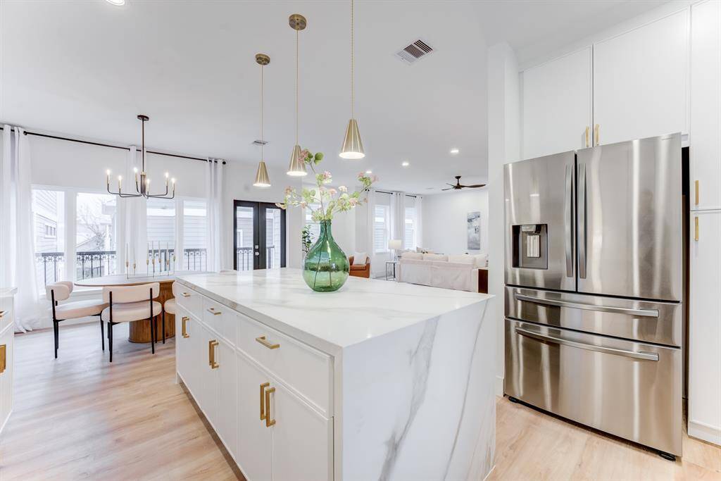 The stainless steel refrigerator  stays with the home. The quartz  island has functioning doors and  cabinets for optimal storage.
