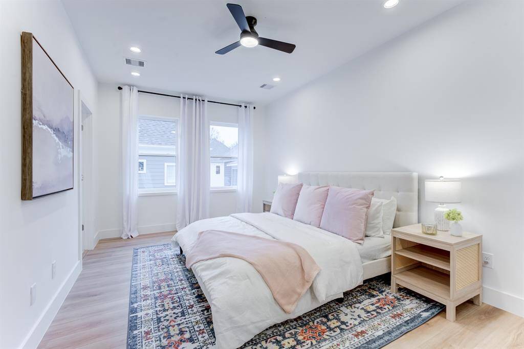 This spacious primary suite  features 2 large windows for  natural light, recessed lighting,  and a ceiling fan.
