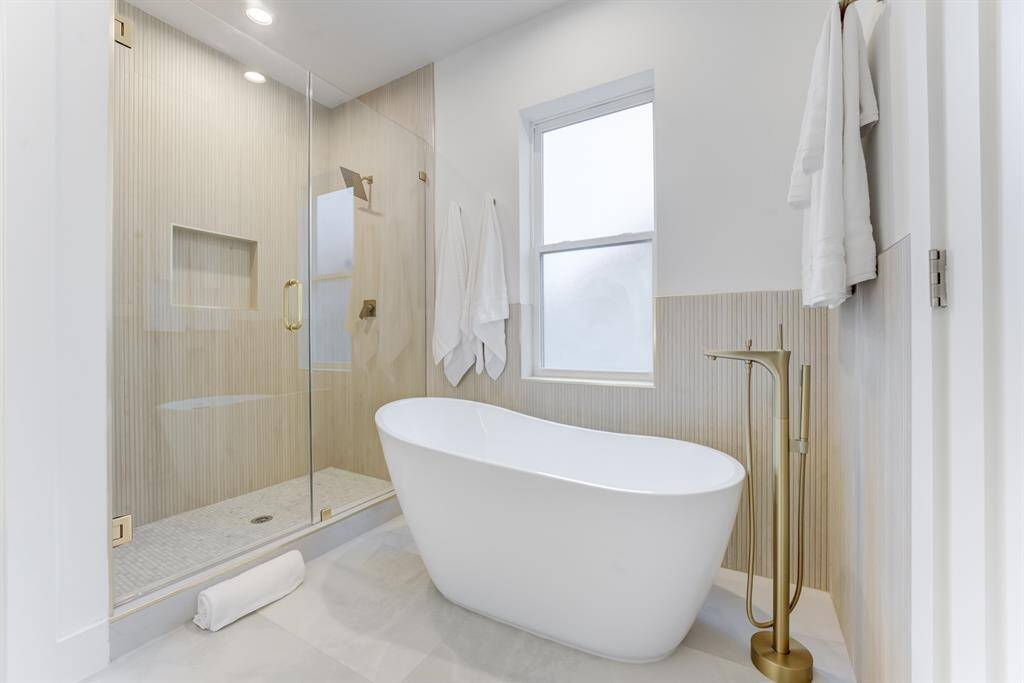 The beautiful porcelain garden tub  and frameless tiled shower with  the large accented window offers a  spa-like experience in the home.