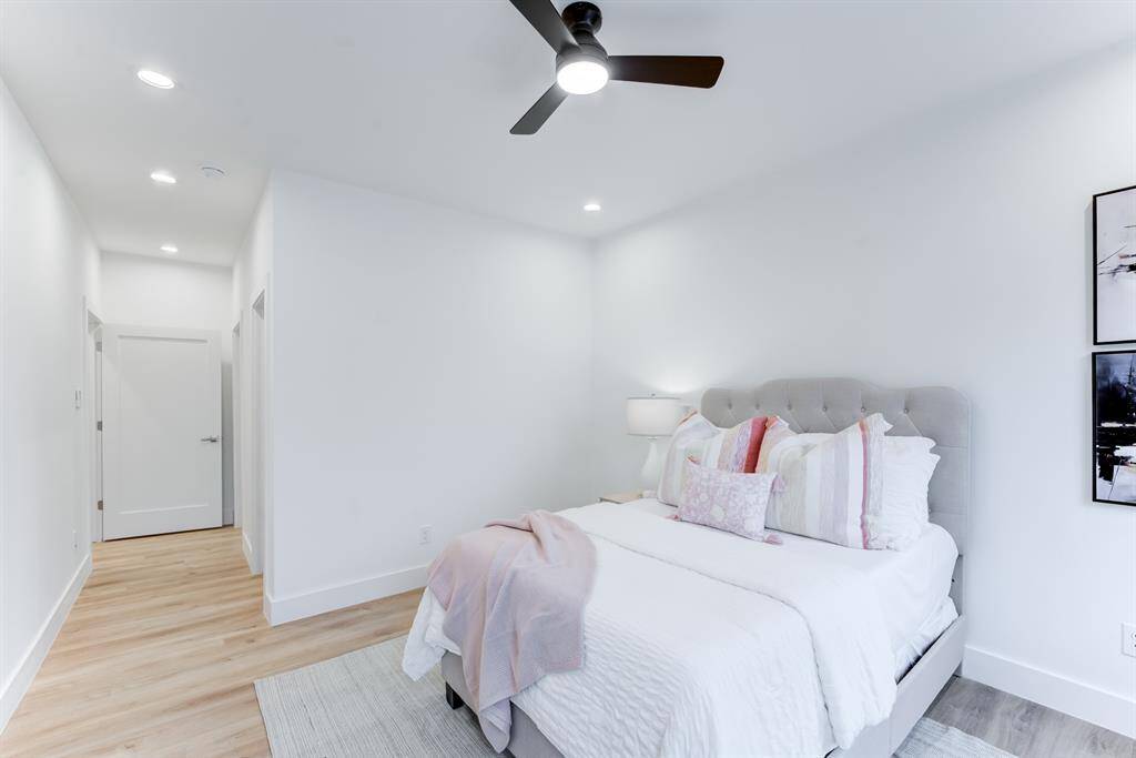 Secondary bedroom with luxury  vinyl plank flooring, recessed  lighting, ceiling fan, and neutral  toned walls.