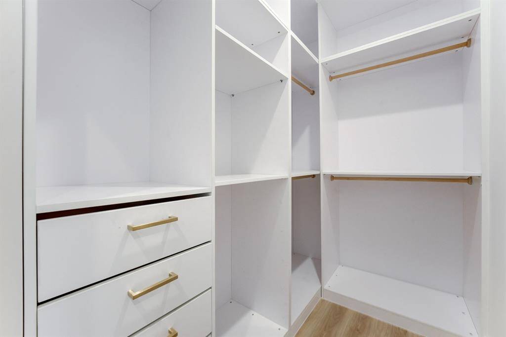The walk-in closet has custom built-in storage, space and drawers with gold hardware.