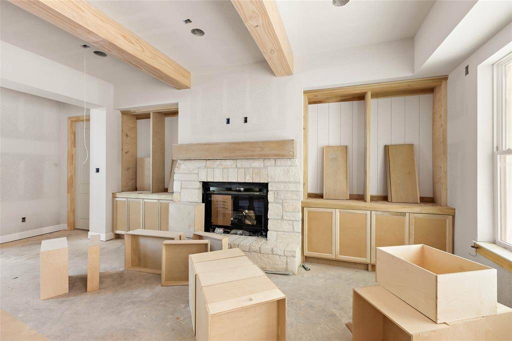 Architectural details in the living room include wood beams, a stone framed fireplace with floating mantle and thoughtful built-ins.