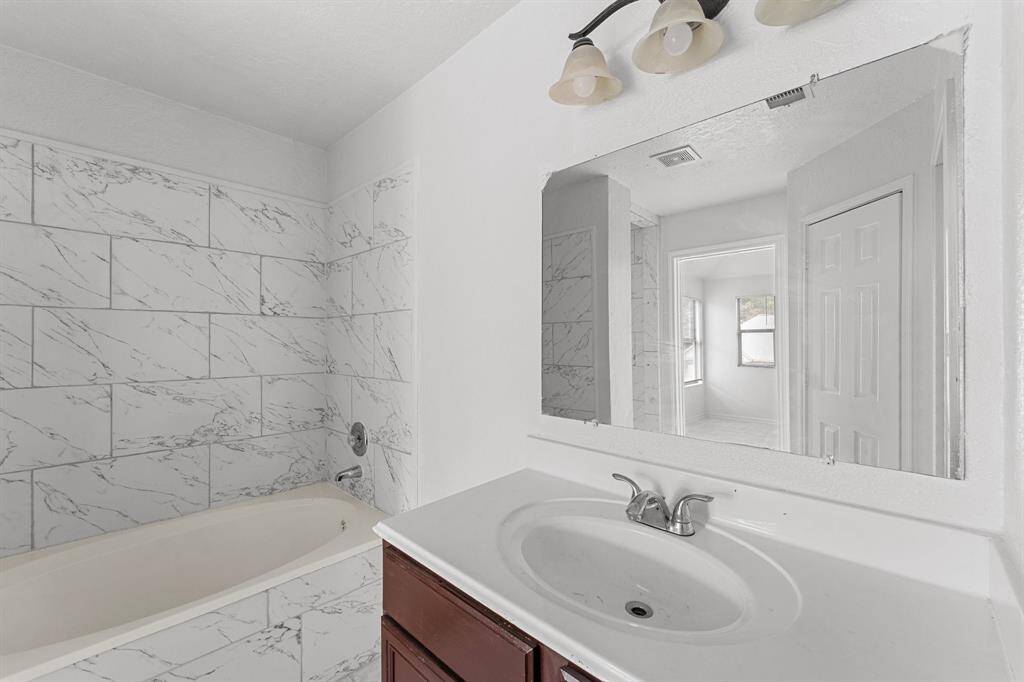 The master bathroom features a soacking tub with tile walls, and the sink has granite countertops and backsplash.