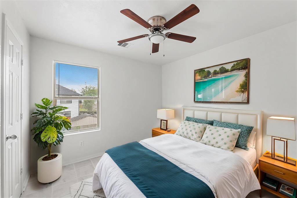 Virtually Staged: This secondary bedroom features tile floors, a ceiling fan, windows with privacy blinds, and a built-in closet.