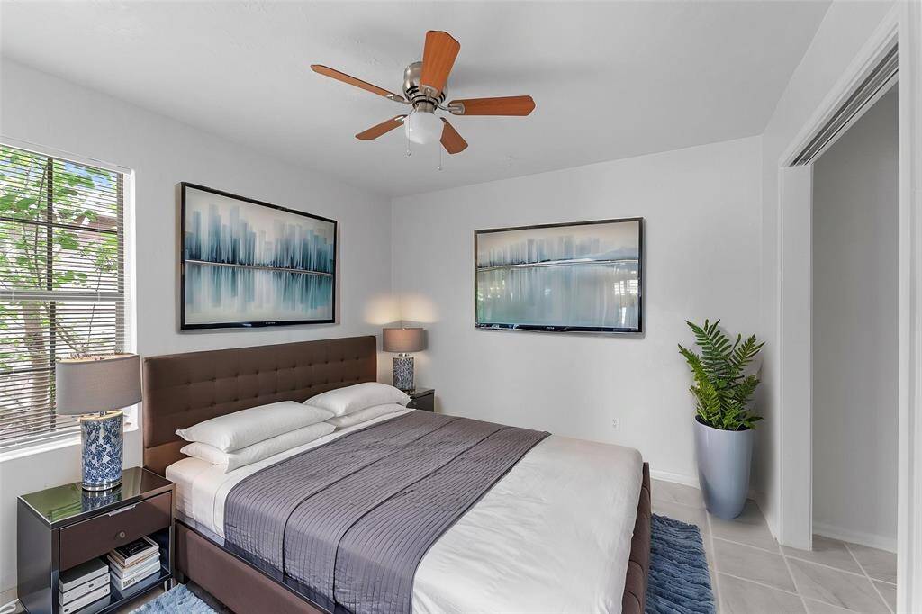 Virtually Staged: This secondary bedroom features tile floors, a ceiling fan, windows with privacy blinds, and a generous built-in closet.