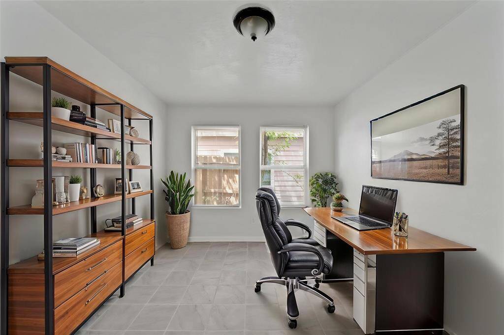 Virtually Staged: Conveniently tucked away in the home is this home office, perfect to get work done. It features tile floors, and windows with privacy blinds.