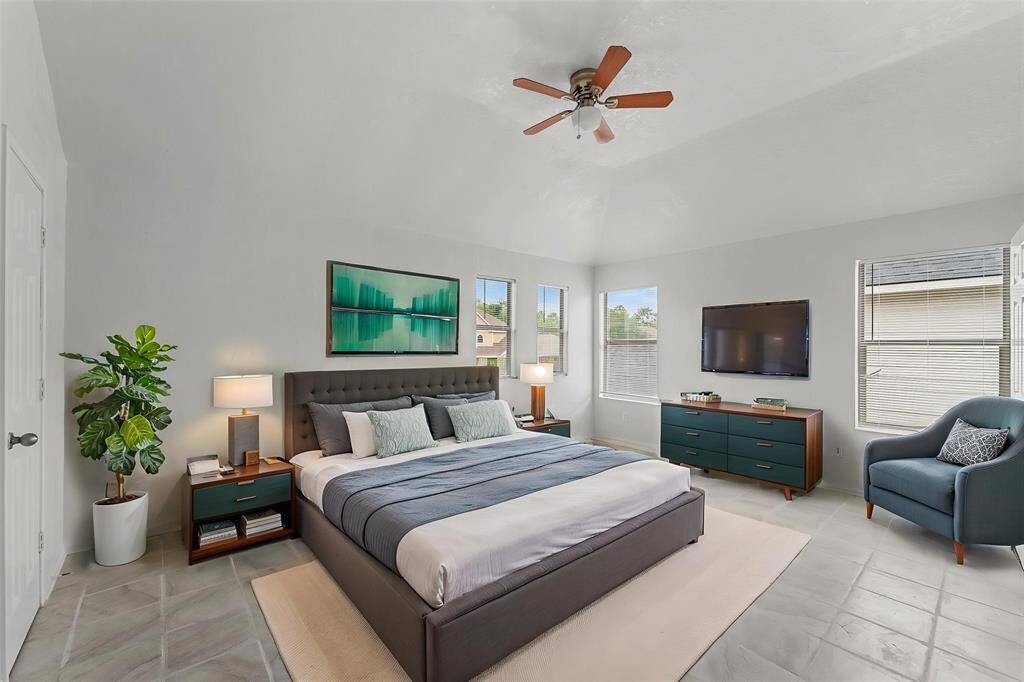 Virtually Staged: A great place to rest after a long day! This primary bedroom features tile floors, a ceiling fan, a built-in closet, and windows with privacy blinds.