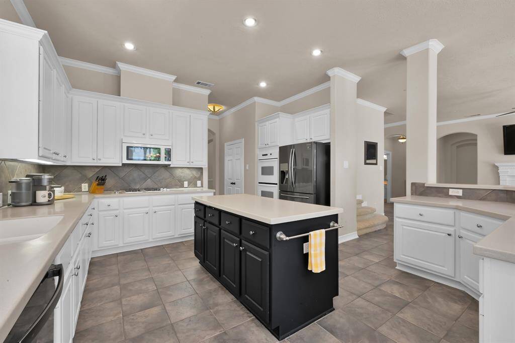 The expansive kitchen with 10' ceilings has an abundance of white cabinetry for all your storage needs. Cooking for a crowd is easy with gas stove, double ovens and microwave. A spacious pantry provides plenty of storage for your dry goods. Across from the pantry and just out of view is the laundry room with cabinets and built in shelving. An interior water shutoff is also easily accessible here.