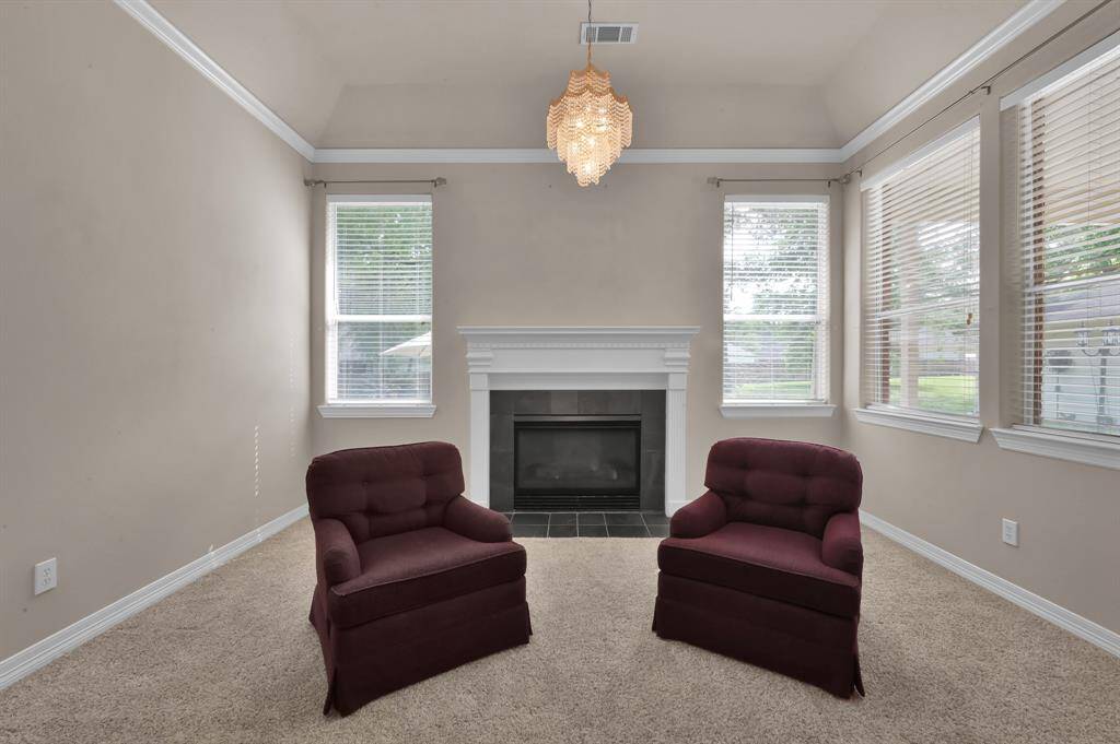 Connected to the primary bedroom is a generous sitting room with multiple tall windows with 2" faux wood blinds for privacy. On cooler evenings, delight in a restful view of the back yard while enjoying the flicker of your personal gas log fireplace with remote starter. Crown molding and a crystal chandelier add a touch of glamour to this room.