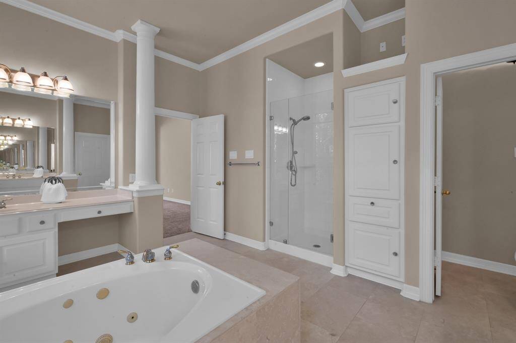 After a long day, pamper yourself in this spa-like bathroom with upgraded Travertine flooring, frameless glass shower and dual vanities and sinks with built-in white medicine cabinets with additional storage beneath. One of the sink areas has a nook for a seat or stool. A built-in wall cabinet provides you more room for your bath essentials with a spot above for a decorative item. A separate water closet allows for private space when sharing the bathroom with others.