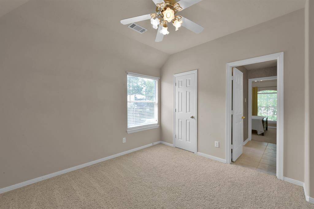 This secondary bedroom is located to the right of the stairs and overlooks the driveway side of the home. It has a gabled ceiling, walk-in closet, and ceiling fan with light. It connects to a Hollywood bath.