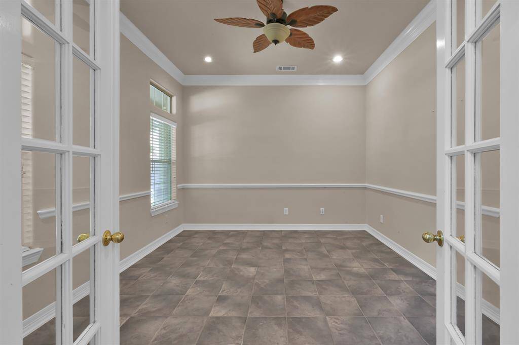Glass-panel French doors lead you into the study located at the front of the home providing privacy and quiet. Even work will be relaxing with views of the wooded front yard or you can close the 2" faux wood blinds when you need full concentration. Transom windows allow extra light to filter in. This room also has crown molding, chair rail and a ceiling fan.