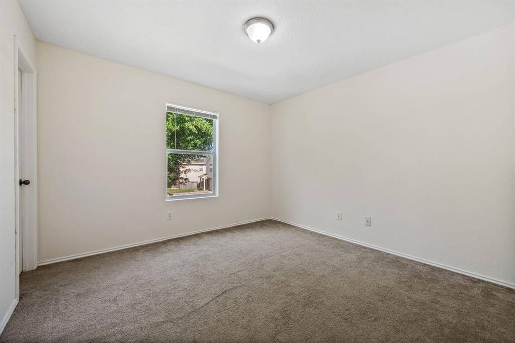 Second bedroom with large window and neutral tones.