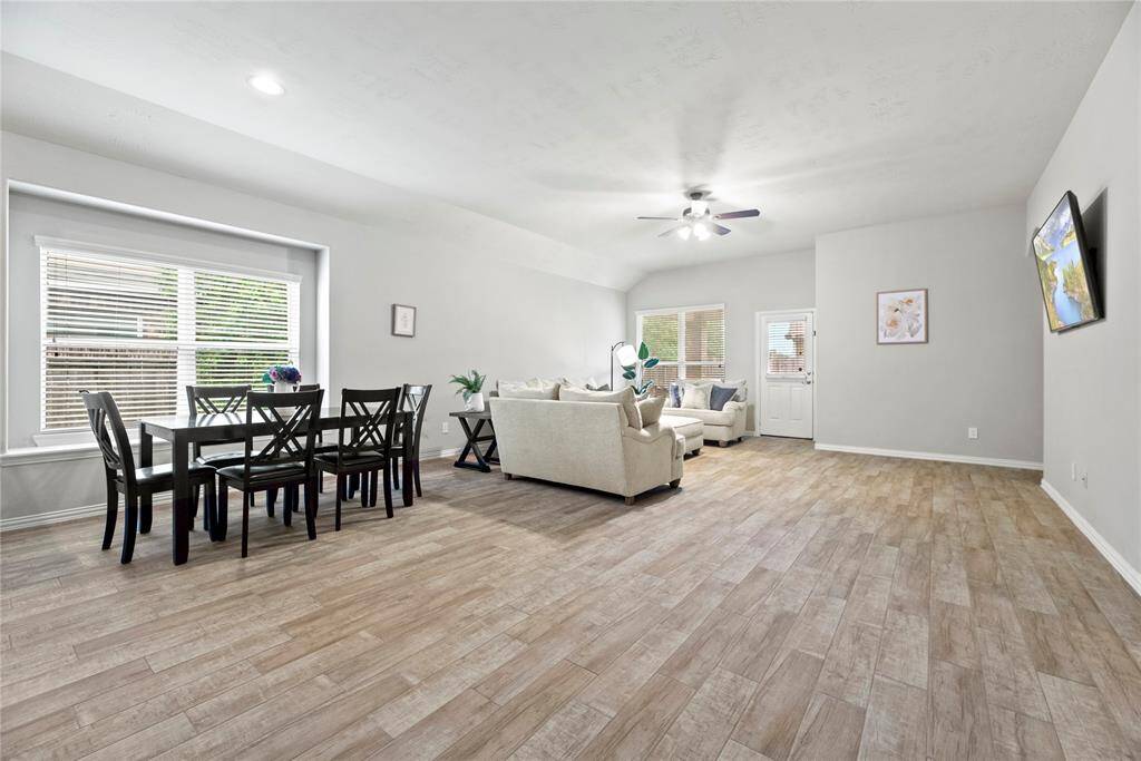 Another look at  the wood-look flooring, neutral walls, and ample natural light from large windows offering a welcoming atmosphere for entertaining or relaxing.