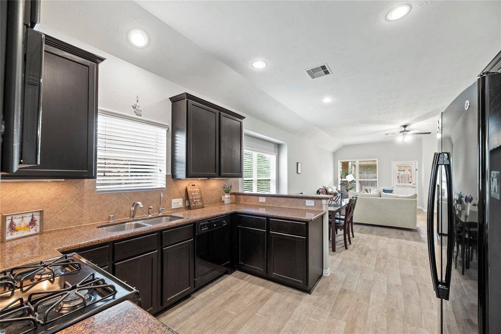 A gas stove, and a double sink with a window above. The countertops are spacious, and with the much needed breakfast bar.
