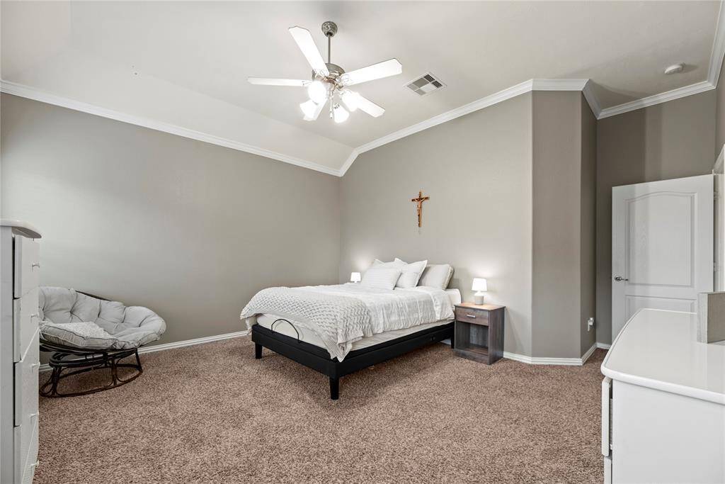 This spacious bedroom features neutral walls, plush carpeting, and a vaulted ceiling.