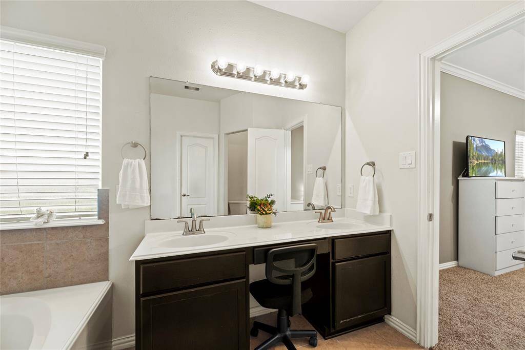 This bathroom features a double sink vanity with a large mirror and modern lighting. It includes ample counter space.