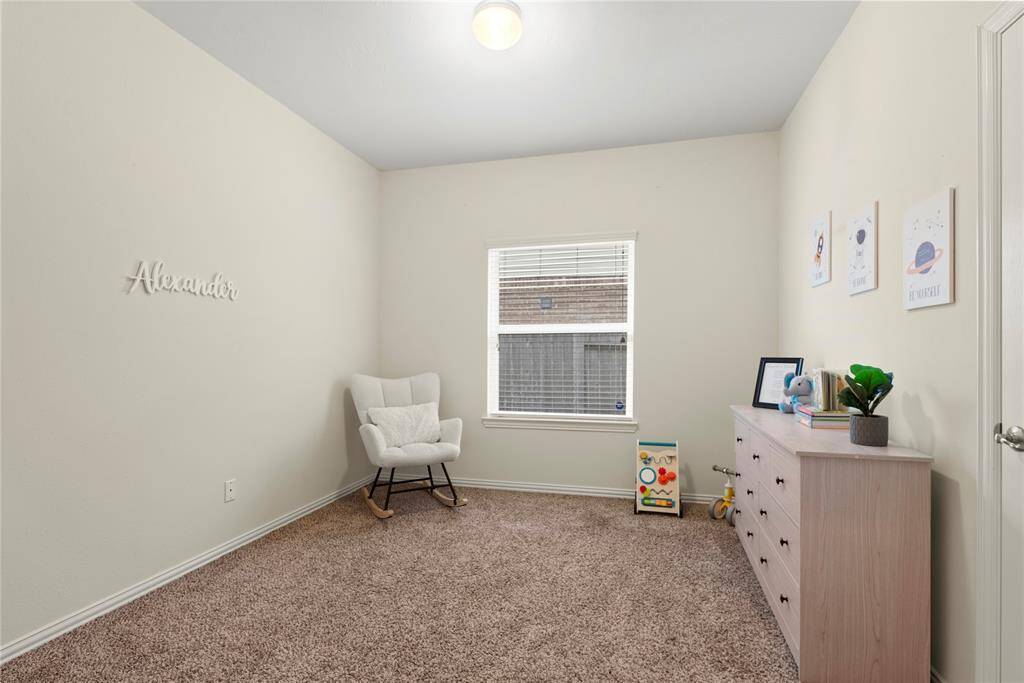 This cozy office or bedroom features a soft carpet, neutral walls, spacious closet, a large window letting in natural light flow thru the room.