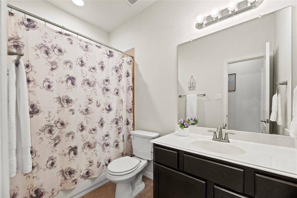 This bathroom features  a sleek vanity with a large mirror, and modern lighting.