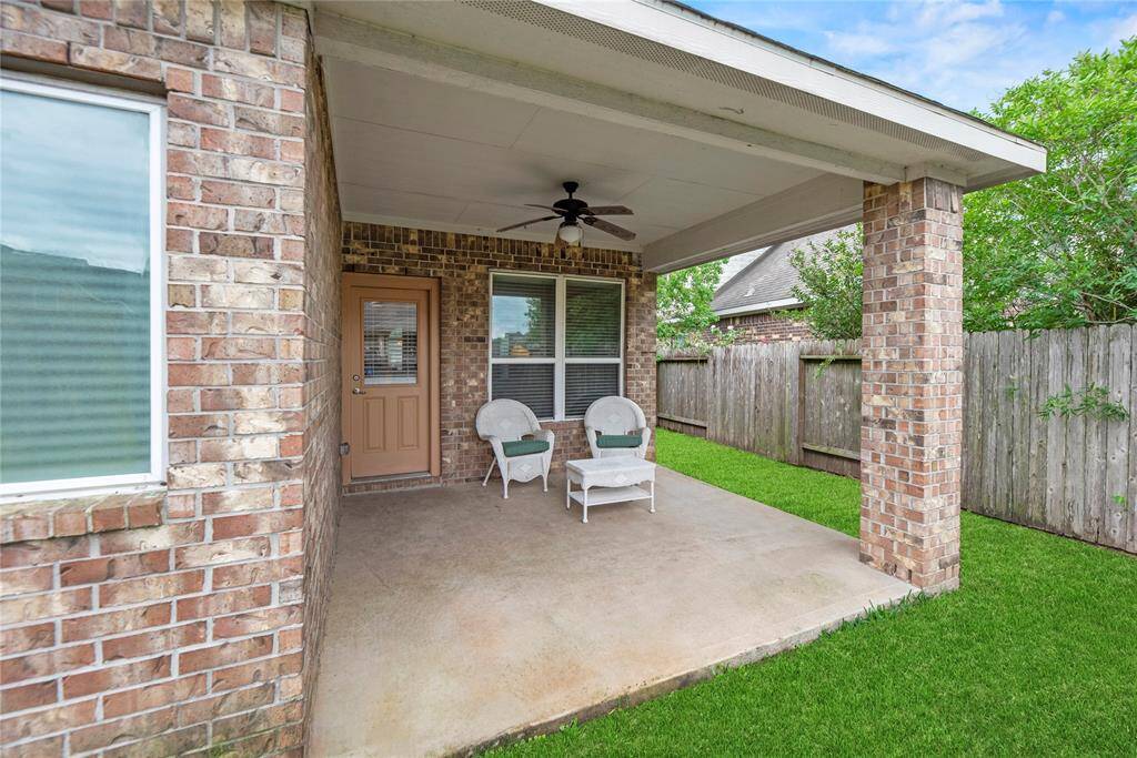 A charming covered patio with brick columns, featuring a ceiling fan and cozy seating.  A private outdoor space perfect for relaxation.