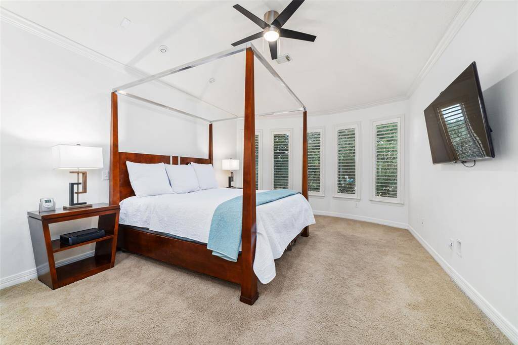 The spacious primary suite detailed with crown moulding, features a wall of windows overlooking the backyard oasis, with access to the patio.