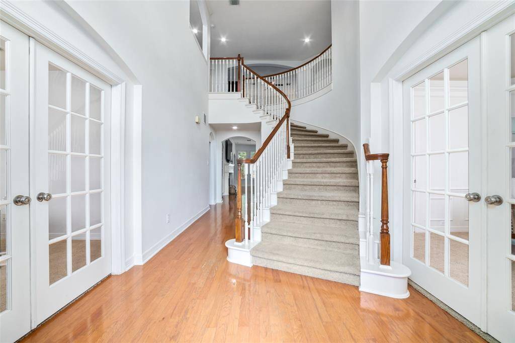 As you enter the foyer, you're greeted with the first of two staircases, along with dramatic, high ceilings.