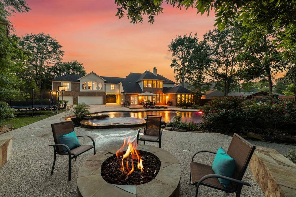 A stunning view of the back of the home, enjoying the gas fire pit area at dusk.