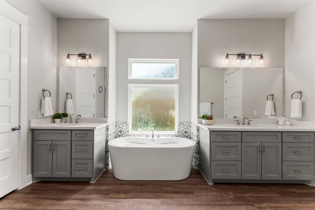 Serene primary Bathroom features dual vanities with separate sinks and relaxing soaker tub surrounded with designer tile.
