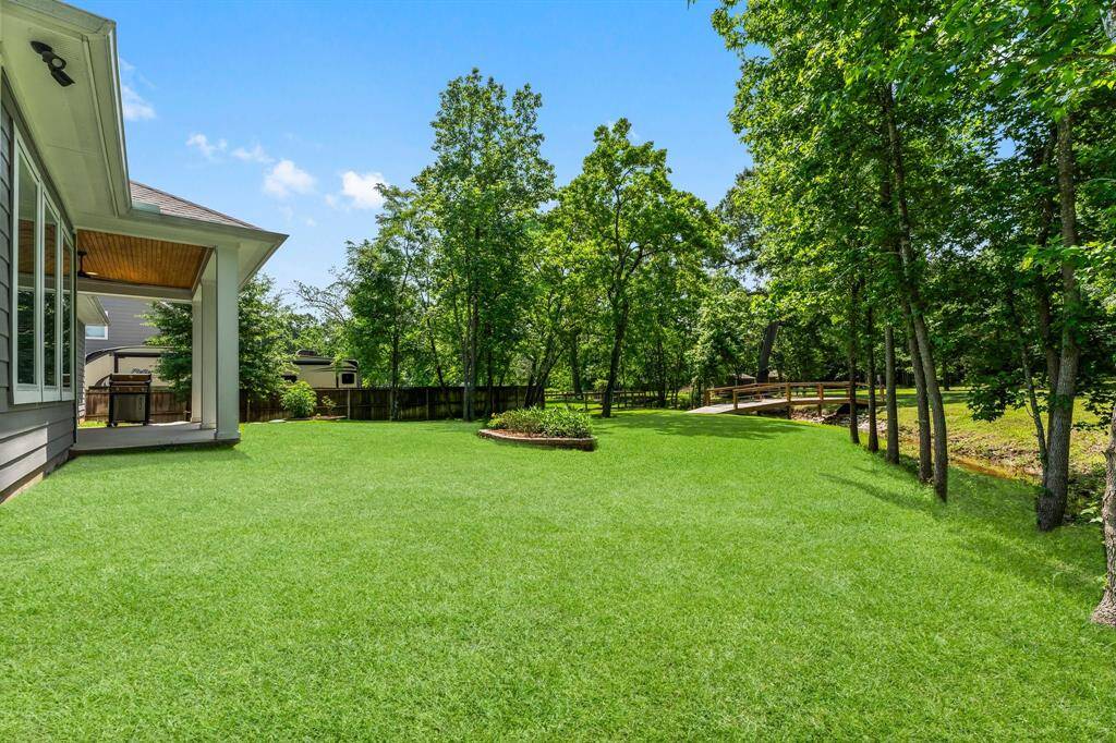 View of the backyard, bridge, and covered patio from the side of the home.