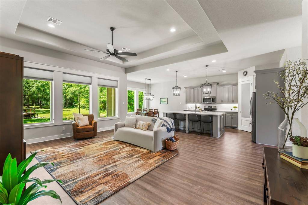 Sunlight floods the space from a wall of oversized windows that stretch across the back of the home.  Soaring tray ceilings add architectural detail.
