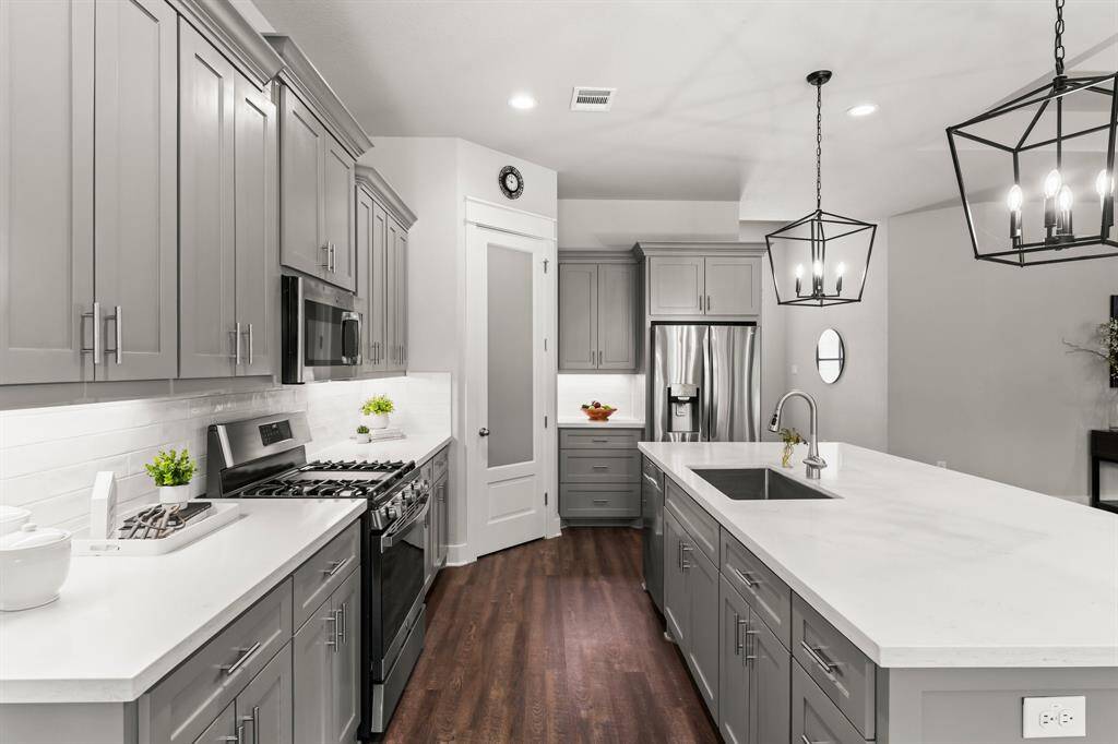 Chef-Inspired Kitchen features over sized Island with Quartz countertops, walk-in pantry, Stainless Steel appliances, Gas stove with griddle, and 42" soft-closing cabinets and drawers.