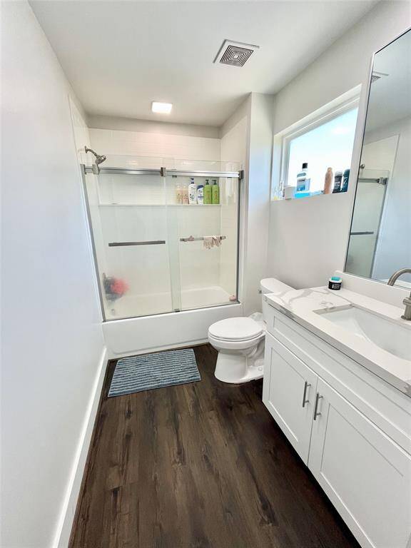 Bathroom with tub, featuring matching quartz countertops, custom cabinets, full size mirror and well lit