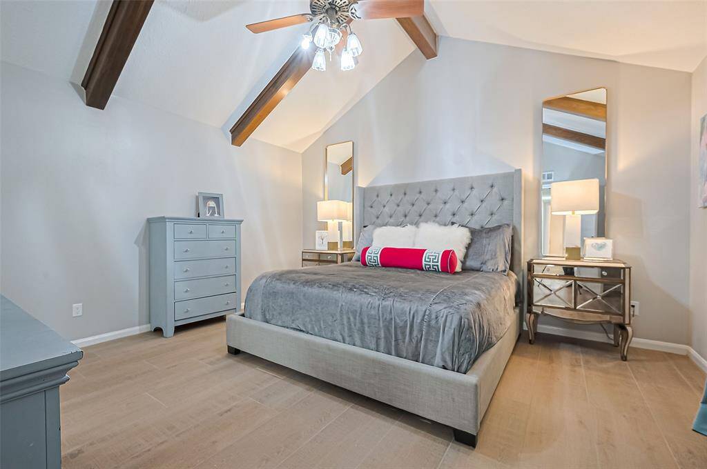 Primary bedroom with a vaulted ceiling and a wooded beam.