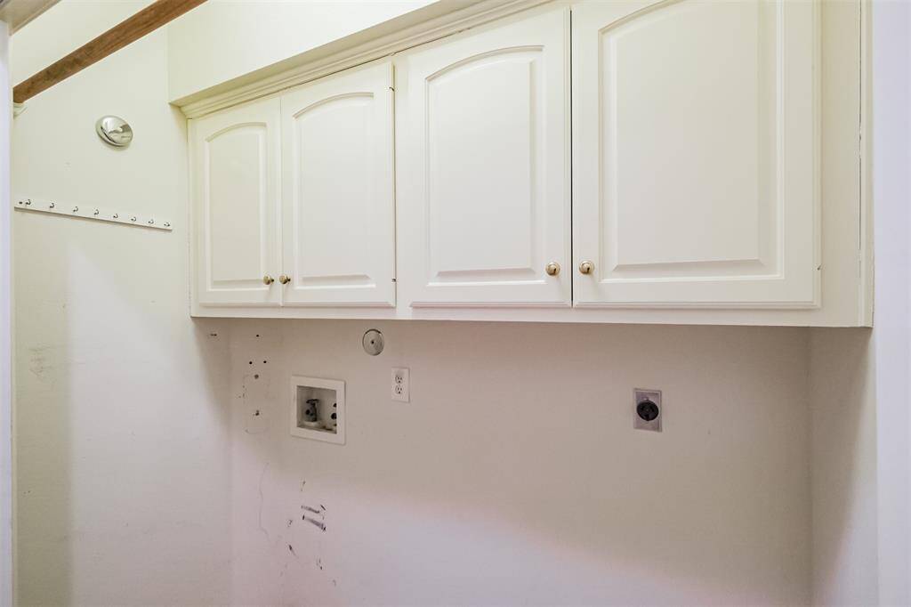 Utility room with hookups for dryer and washer. Storage space in cabinets above.