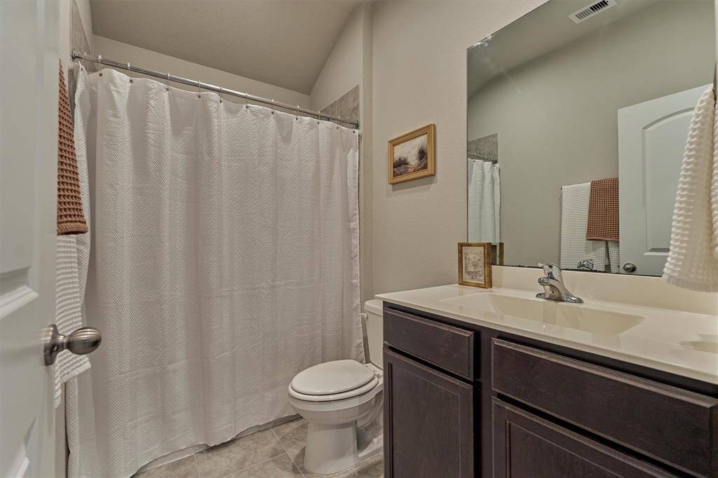 This bathroom includes a tub/shower combination and large vanity and sink.