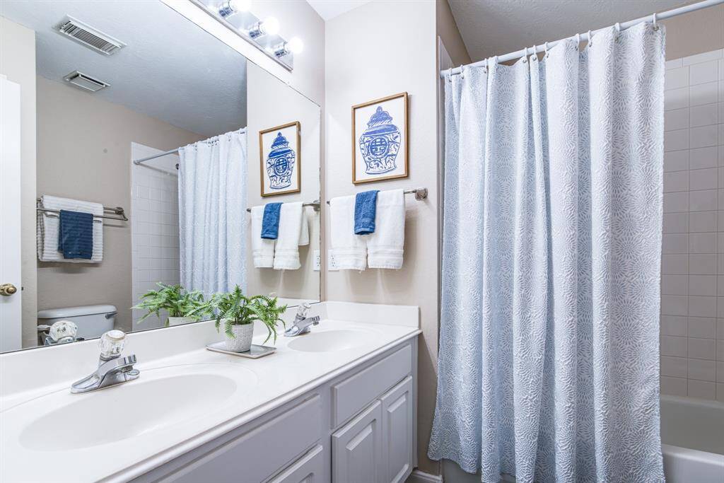 Guest hall bath with double sinks and tub/shower combination.
