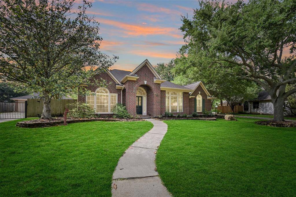 Nestled near the bend of a quiet street in sought-after Wilderness Trails, this stately red brick one-story exudes curb appeal with mature trees, manicured landscaping, a gated drive, and a charming arched entry—all within highly acclaimed Friendswood ISD.
