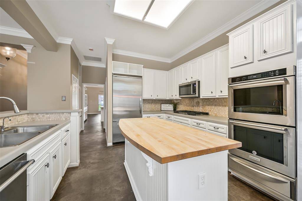The chef of the house will love this well-equipped kitchen with freshly painted cabinetry, double ovens, a 5-burner gas cooktop, built-in microwave, a concealed control dishwasher, a built-in fridge, and a spacious butcher block island for prep or casual dining.