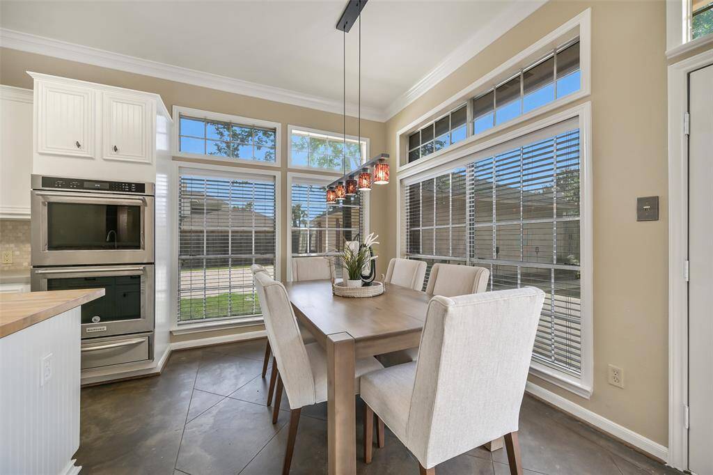 This chic breakfast nook is surrounded by windows with peaceful views of the backyard oasis, accented by modern pendant lighting and plenty of natural light for a warm, welcoming dining experience.
