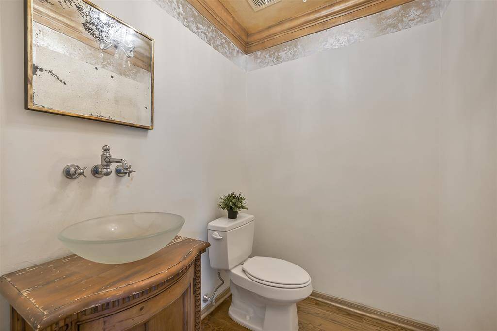 Just off of the main hallway, you'll find this stylish half bath that features a custom vanity with a vessel sink, a wall-mounted faucet, and decorative ceiling trim for added character. Perfectly positioned for house guests!