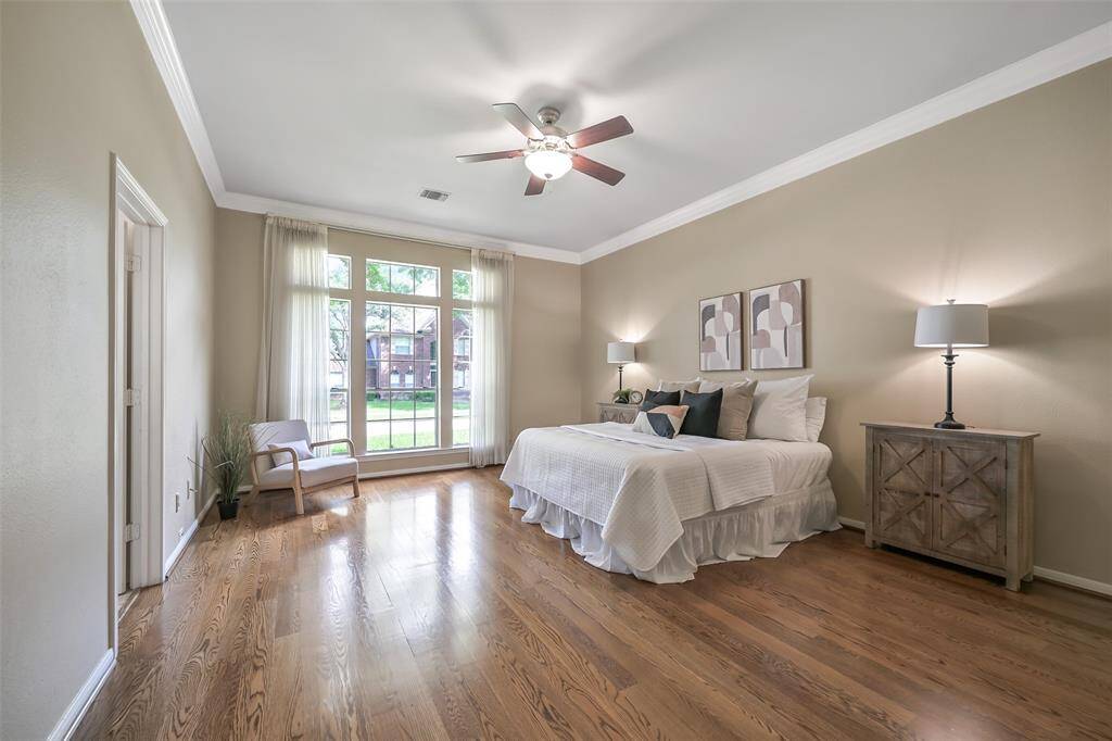 Tucked away from the hustle and bustle of a busy house, this spacious primary suite offers rich hardwood flooring, crown molding, and a wall of windows that bathe the room in natural light while offering tranquil views of the front lawn.