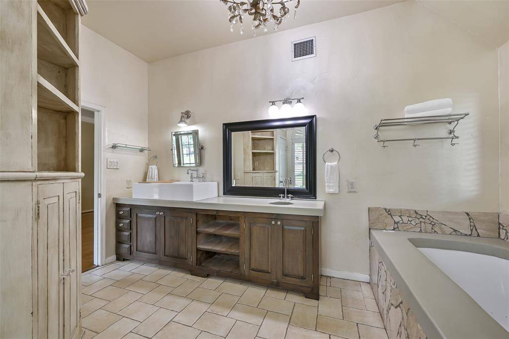 Dual vanities, ample under-cabinet storage, and a built-in linen tower enhance the functionality of this luxurious primary bath—offering comfort and organization in equal measure.