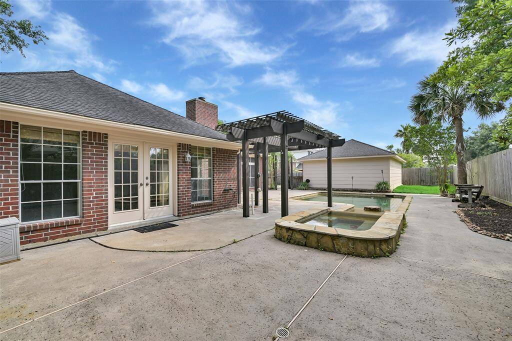 French doors from the spacious game room lead to a private backyard oasis with a sparkling pool and elevated spa, all beneath a stylish pergola—perfect for entertaining or relaxing in the shade.