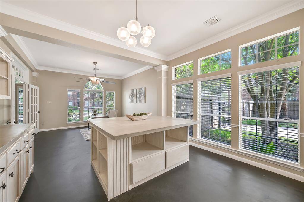 The former formal dining room was thoughtfully transformed into a spacious workspace with a wall of built-in cabinetry, open shelving, and an oversized (removable) island—perfect for a home business, creative studio, or home schooling classroom!