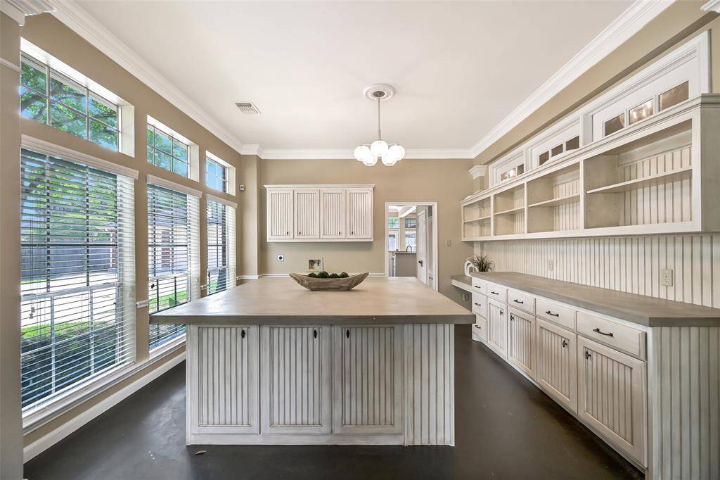 The former formal dining room was thoughtfully transformed into a spacious workspace with a wall of built-in cabinetry, open shelving, and an oversized (removable) island—perfect for a home business, creative studio, or home schooling classroom!