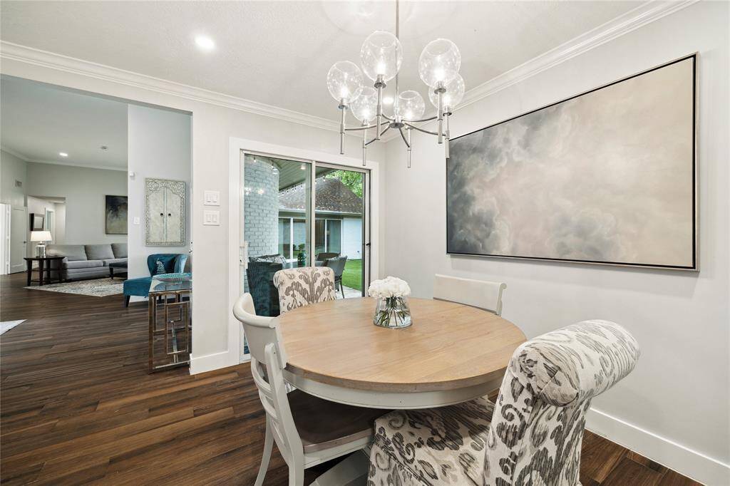 A sunny breakfast nook bathed in natural light, anchored by a sleek modern pendant light, with glass sliding doors framing tranquil views of the covered patio.